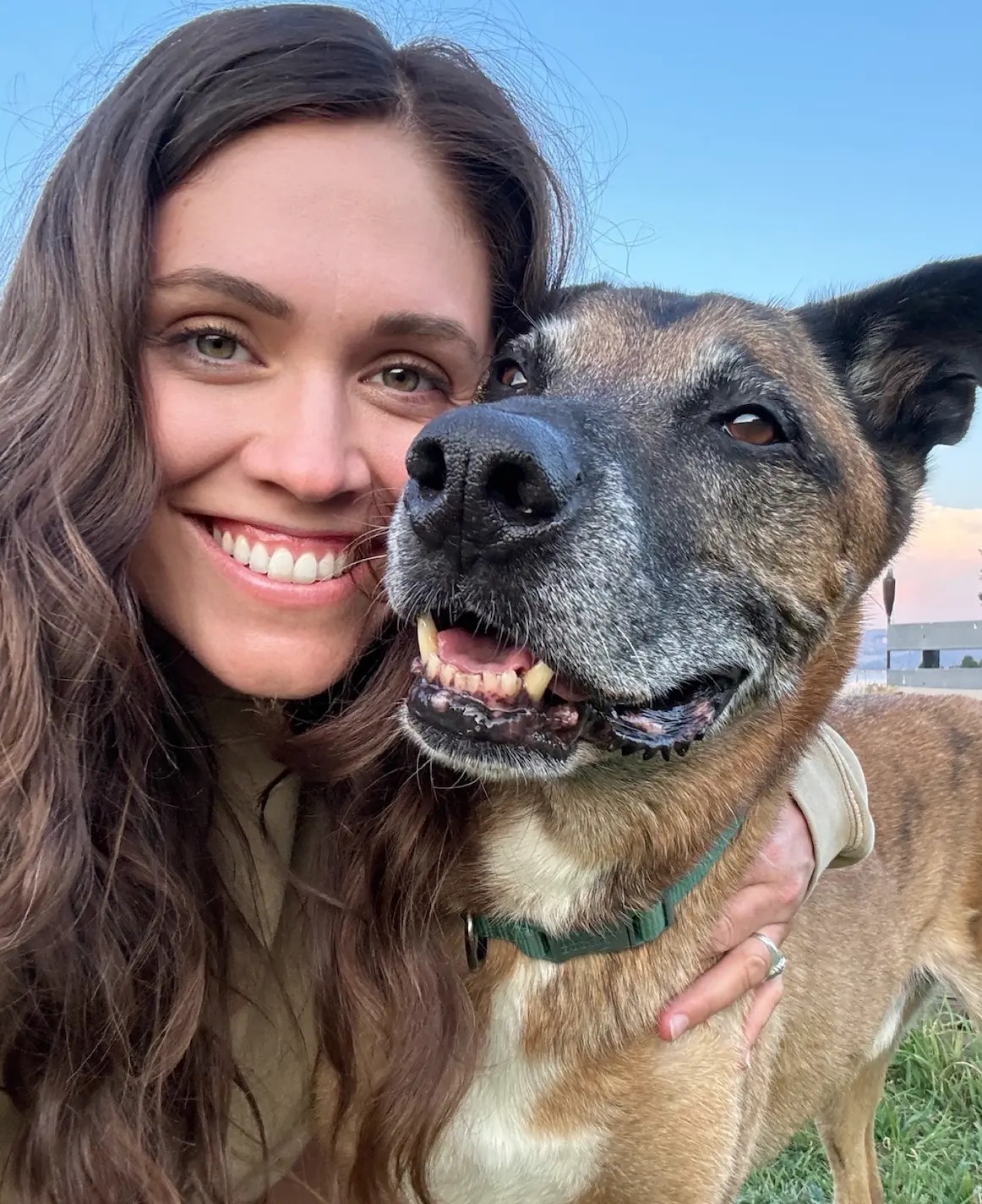 Brooke smiling head-to-head with her dog outdoors at golden hour